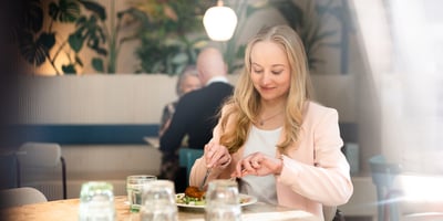 Nainen istuu ruokapöydässä syömässä lounasta